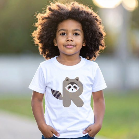 Boy wearing a white cotton t shirt with the letter R in the shape of a raccoon illustration, hands in pocket