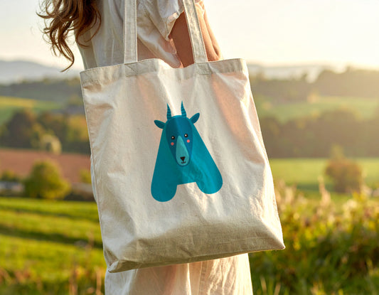 A woman carrying a tote bag with the letter “A” in the shape of an antelope illustration, standing on a blurry autumn background.