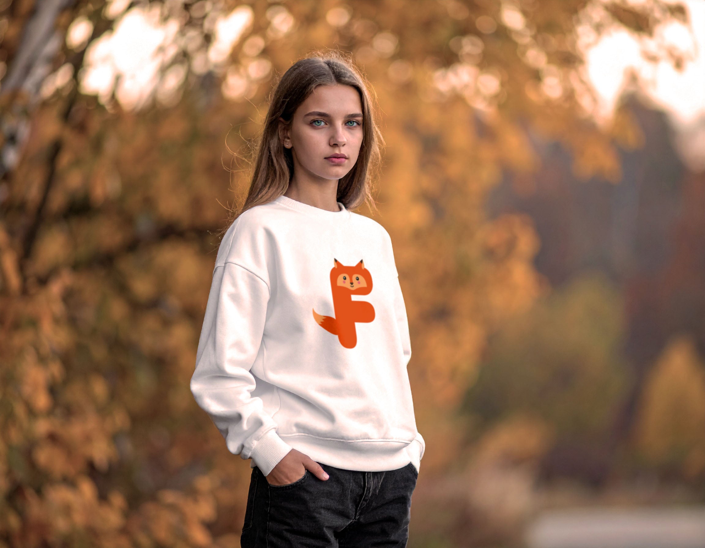 Teenage girl wearing a white sweatshirt with a Letter L as an illustration of a fox in an autumn setting
