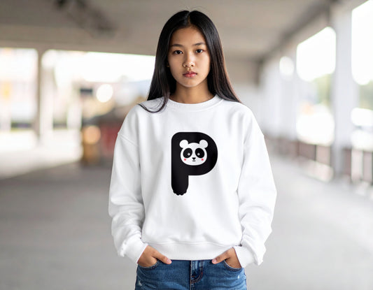A teenage boy wearing a white crewneck sweatshirt with the letter P in the shape of a panda illustration, standing, blurry indoor setting.