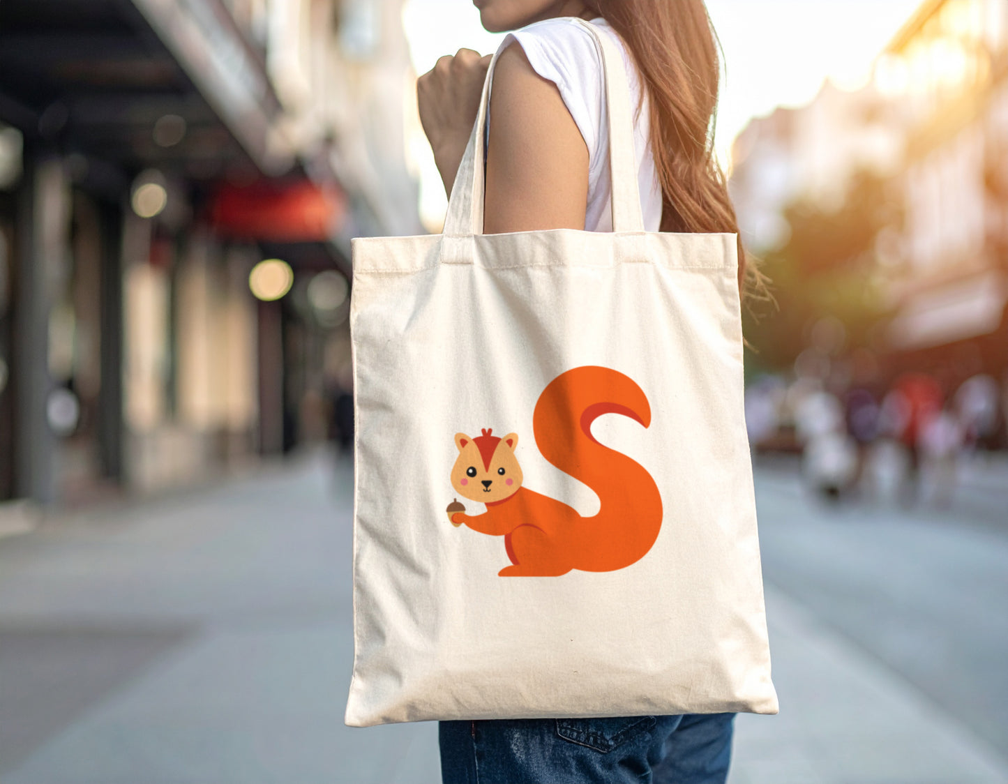 A red haired woman carrying an oyster tote bag with the letter S in the shape of a squirrel illustration on a blurred city street background.